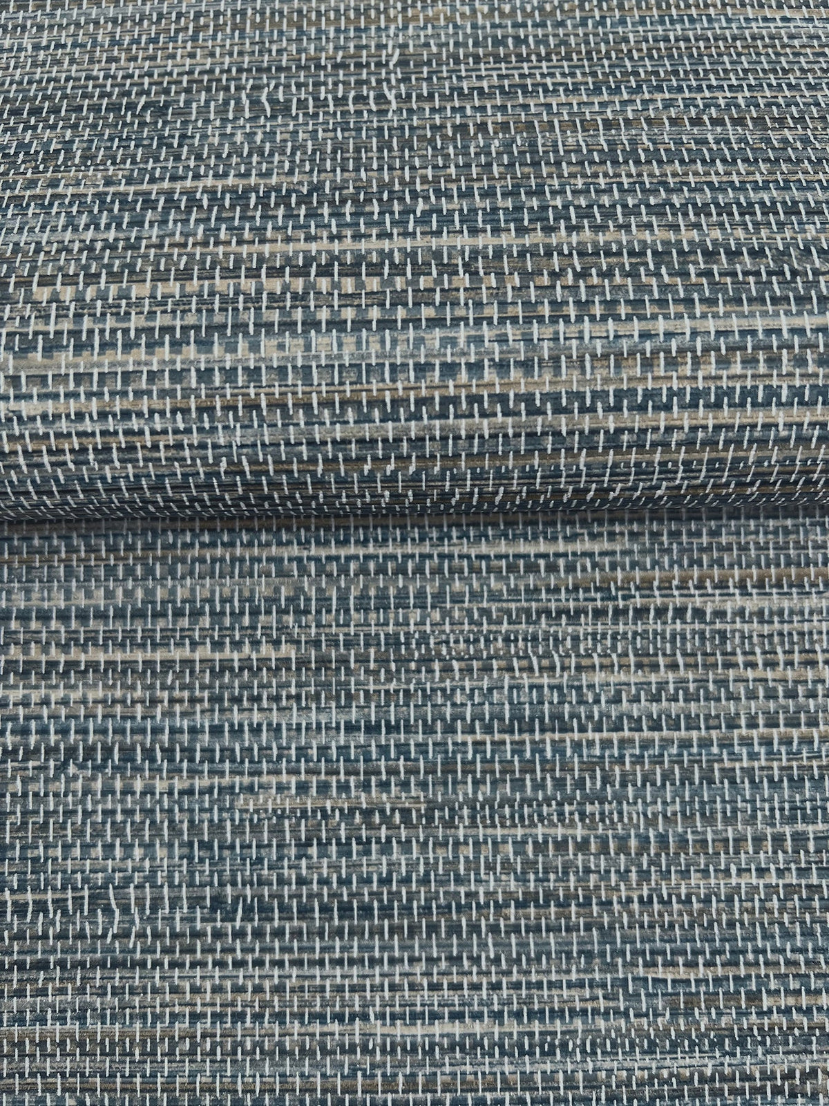 A close-up of dark blue and grey Winn Faux Grasscloth Wallpaper by York Wallcoverings, featuring a woven, horizontal texture.