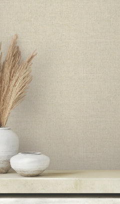 Clarkson Woven Wallpaper in beige with a fine texture sits behind two ceramic vases filled with dried ornamental grass.