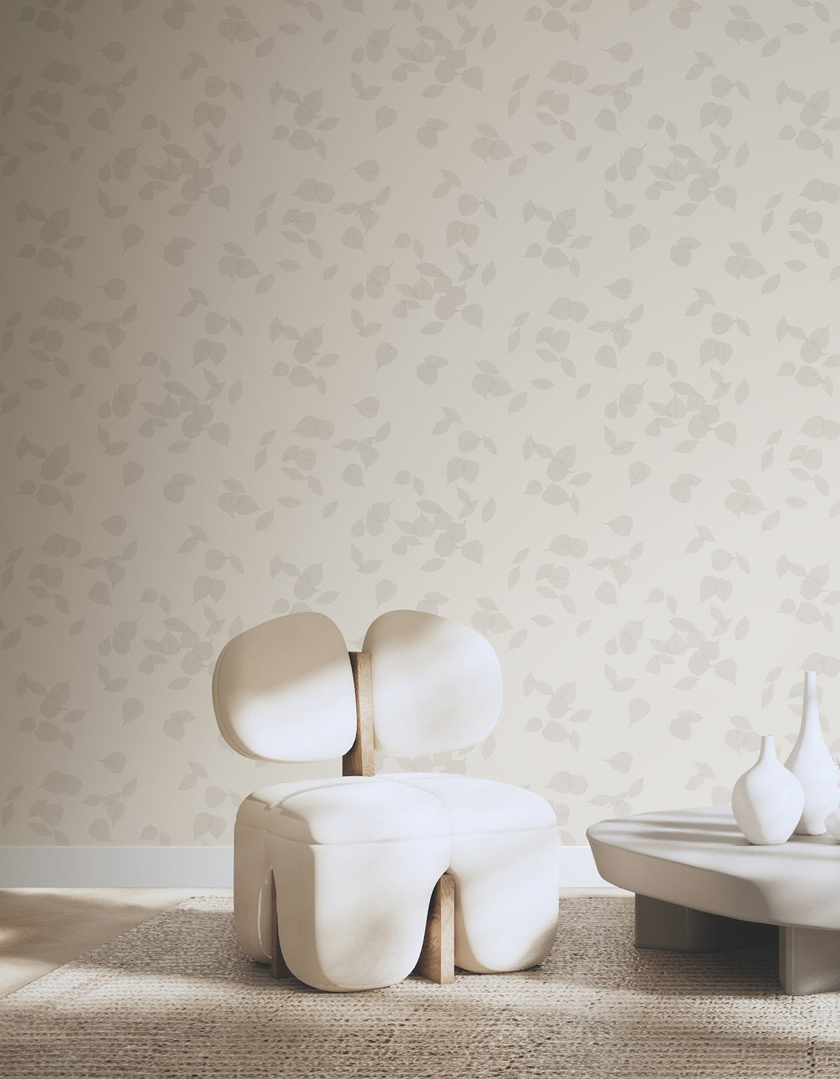 Myles Leaves Wallpaper by York Wallcoverings featuring a repeating pattern of light-colored leaves on a neutral background, shown behind a modern white chair and a low table.