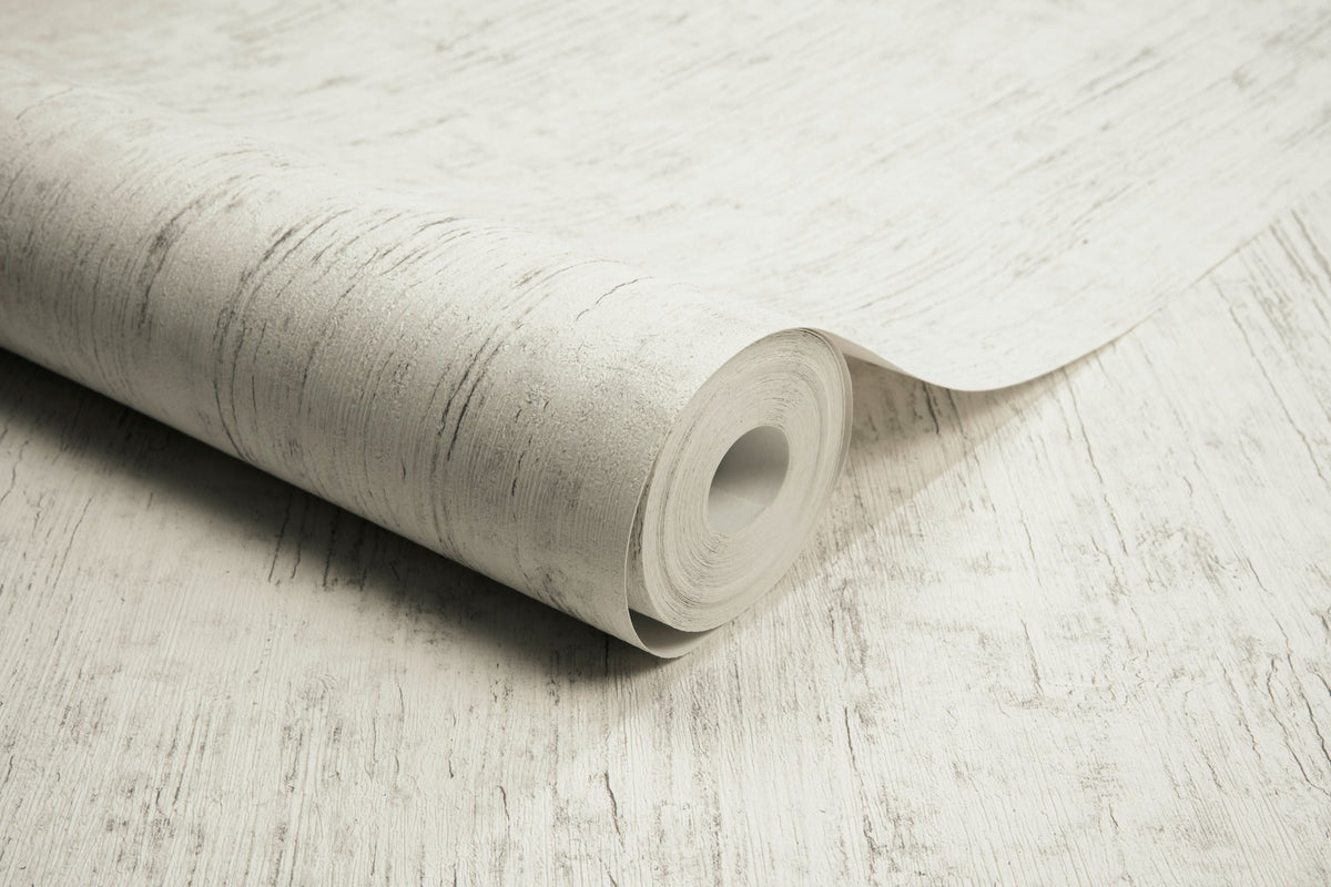 A roll of Chesapeake Ramona Distressed Texture Wallpaper by York Wallcoverings, featuring a light-colored, subtly textured pattern, is partially unrolled on a matching surface.