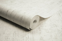 A partially unrolled roll of Chesapeake Ramona Distressed Texture Wallpaper by York Wallcoverings, featuring a light-colored, textured design with subtle gray lines and patterns on a matching surface.