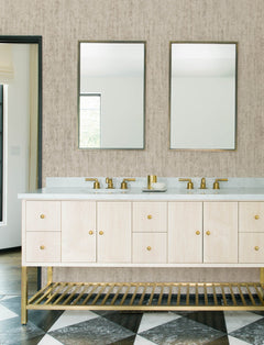 Modern bathroom featuring a double sink vanity with gold faucets and hardware, two rectangular mirrors, light wood cabinets, a black-and-white geometric tile floor, and Chesapeake Ramona Distressed Texture Wallpaper by York Wallcoverings.