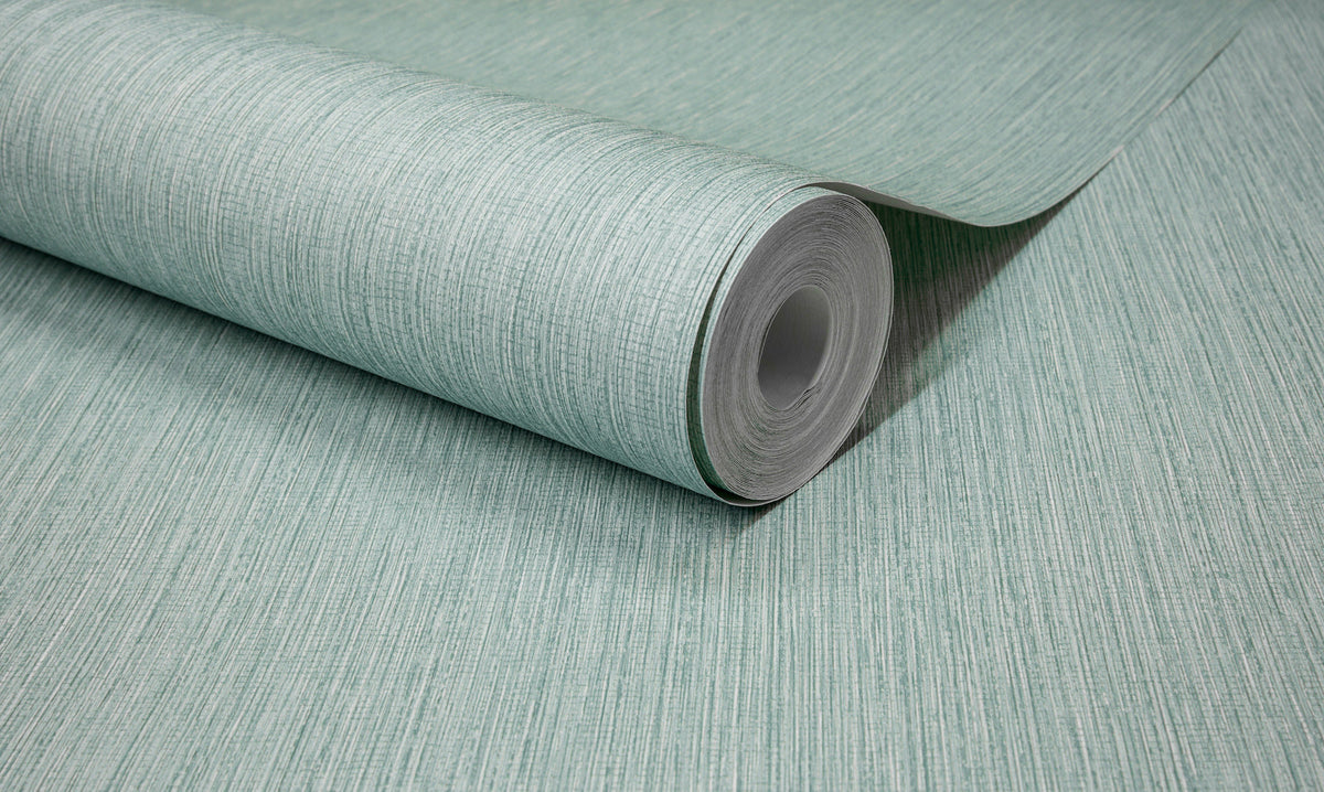 A close-up of a roll of Chesapeake Elijah Texture Wallpaper by York Wallcoverings, partially unrolled on a flat surface, showcases its light green hue and subtle vertical texture.
