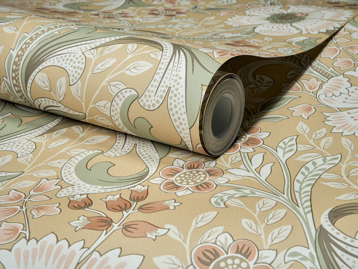 A partially unrolled roll of Chesapeake Liora Floral Trail Wallpaper by York Wallcoverings, showcasing a vintage-inspired floral pattern in muted beige, green, and orange tones with elegant flowers, leaves, and swirling details against a coordinated background.
