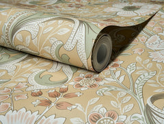 A partially unrolled roll of Chesapeake Liora Floral Trail Wallpaper by York Wallcoverings, showcasing a vintage-inspired floral pattern in muted beige, green, and orange tones with elegant flowers, leaves, and swirling details against a coordinated background.
