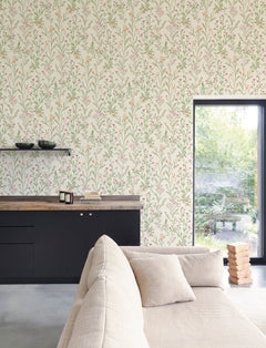 A modern living room with a beige sofa, black cabinets, wooden countertop, and a window overlooking a green garden features York Wallcoverings’ Chesapeake Laverne Wildflowers Wallpaper. Two black bowls and a stack of wooden blocks are also visible in the scene.