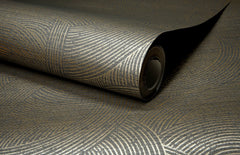 A close-up of a rolled sheet of Chesapeake Harrison Swirling Geometric Wallpaper by York Wallcoverings, showcasing a metallic gold and gray pattern with concentric circles and intersecting lines.