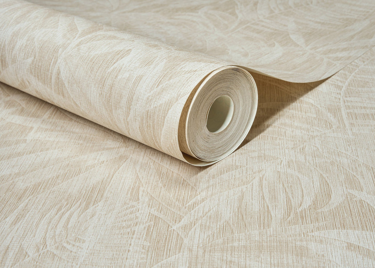 A roll of York Wallcoverings Chesapeake Sonny Fronds Wallpaper, featuring a subtle leafy pattern in beige, lies partially unrolled on a matching surface.