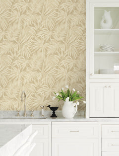 Bright white kitchen with marble countertops, Chesapeake Sonny Fronds Wallpaper by York Wallcoverings in beige, tulips in a white pitcher, black bird decor, and glass-front cabinets holding plates and a white ceramic rooster.