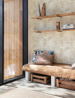 Sure! Here’s the rewritten sentence incorporating the given product: A cozy nook with a tan cushioned bench, colorful pillows, wooden crate storage below, wooden shelves with books and decor above, and a large window letting in natural light—all accented by Chesapeake Cassandra Block Geometric Wallpaper from York Wallcoverings.