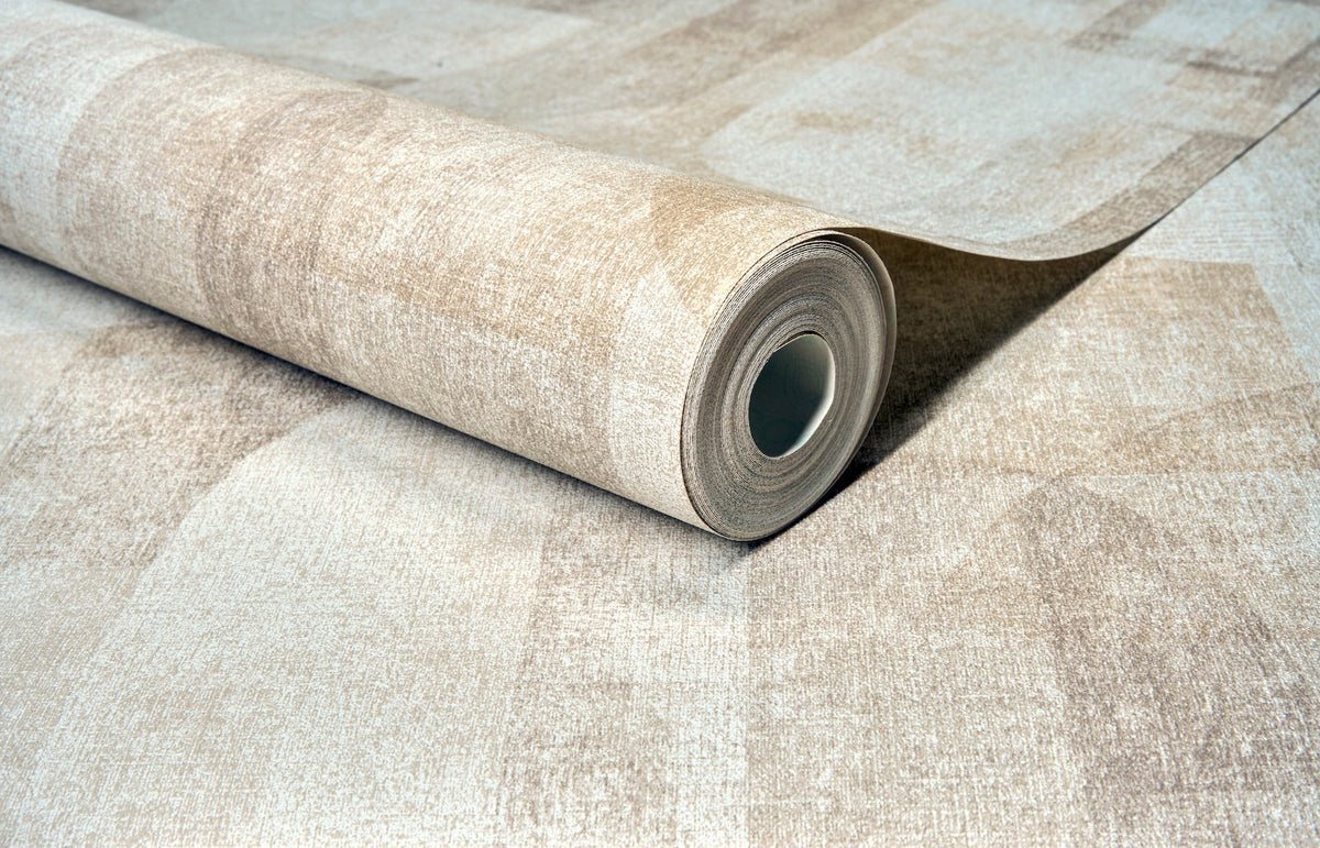 A close-up of a partially unrolled roll of York Wallcoverings Chesapeake Cassandra Block Geometric Wallpaper in beige, lying on a matching flat surface.
