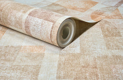 A close-up of the Chesapeake Cassandra Block Geometric Wallpaper by York Wallcoverings, featuring a beige and brown textured geometric pattern, partially unrolled on a matching surface.