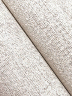 Close-up of two pieces of Chesapeake Tansy Distressed Wallpaper by York Wallcoverings overlapping diagonally, showcasing a subtle horizontal and vertical grain pattern on the textured beige surface.