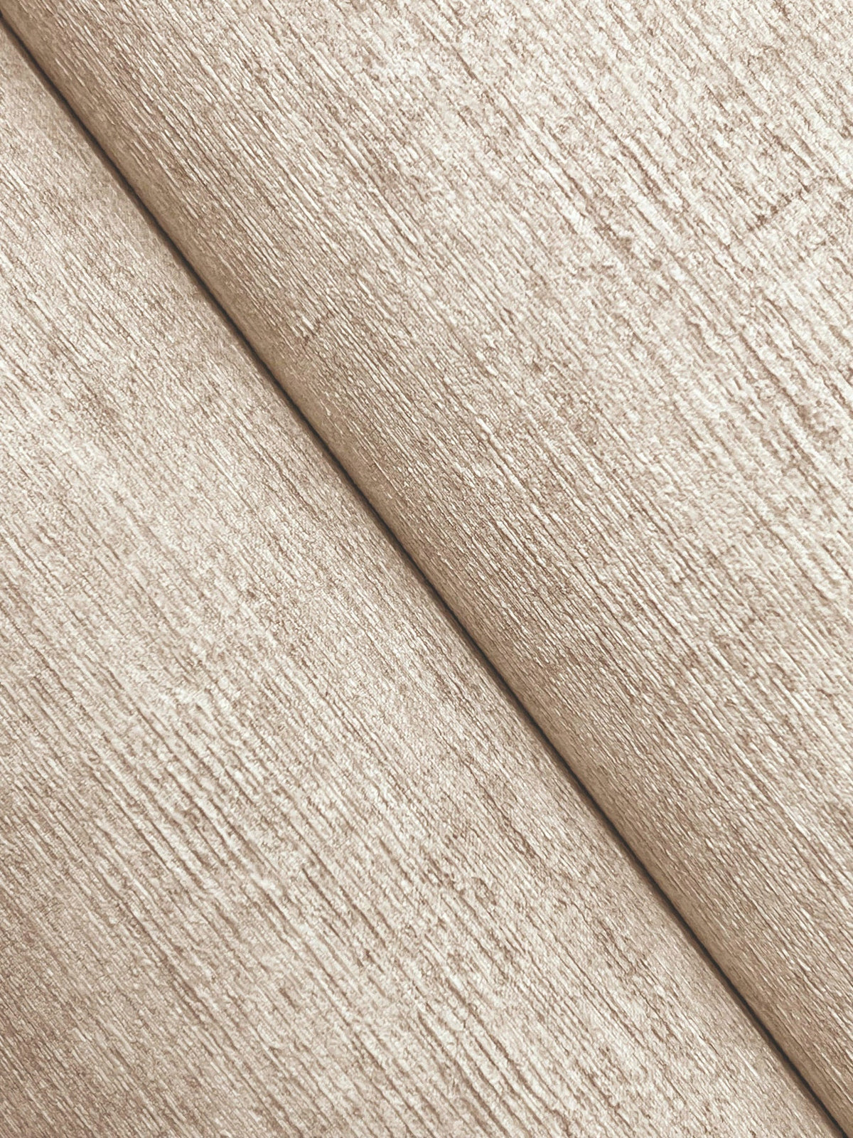 Close-up of Chesapeake Tansy Distressed Wallpaper by York Wallcoverings, featuring two beige, textured sections with a diagonal seam running from the bottom left to the top right, highlighting its rough, woven-like pattern and subtle shadow along the seam.