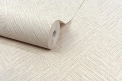 A roll of Chesapeake Hollis Textured Diamond Wallpaper by York Wallcoverings in beige, featuring a herringbone-inspired diamond pattern with textured diagonal lines for a woven appearance, is partially unrolled on a flat surface.