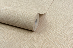 A roll of Chesapeake Hollis Textured Diamond Wallpaper by York Wallcoverings in beige, featuring a textured geometric pattern, is partially unrolled on a matching wallpapered surface.