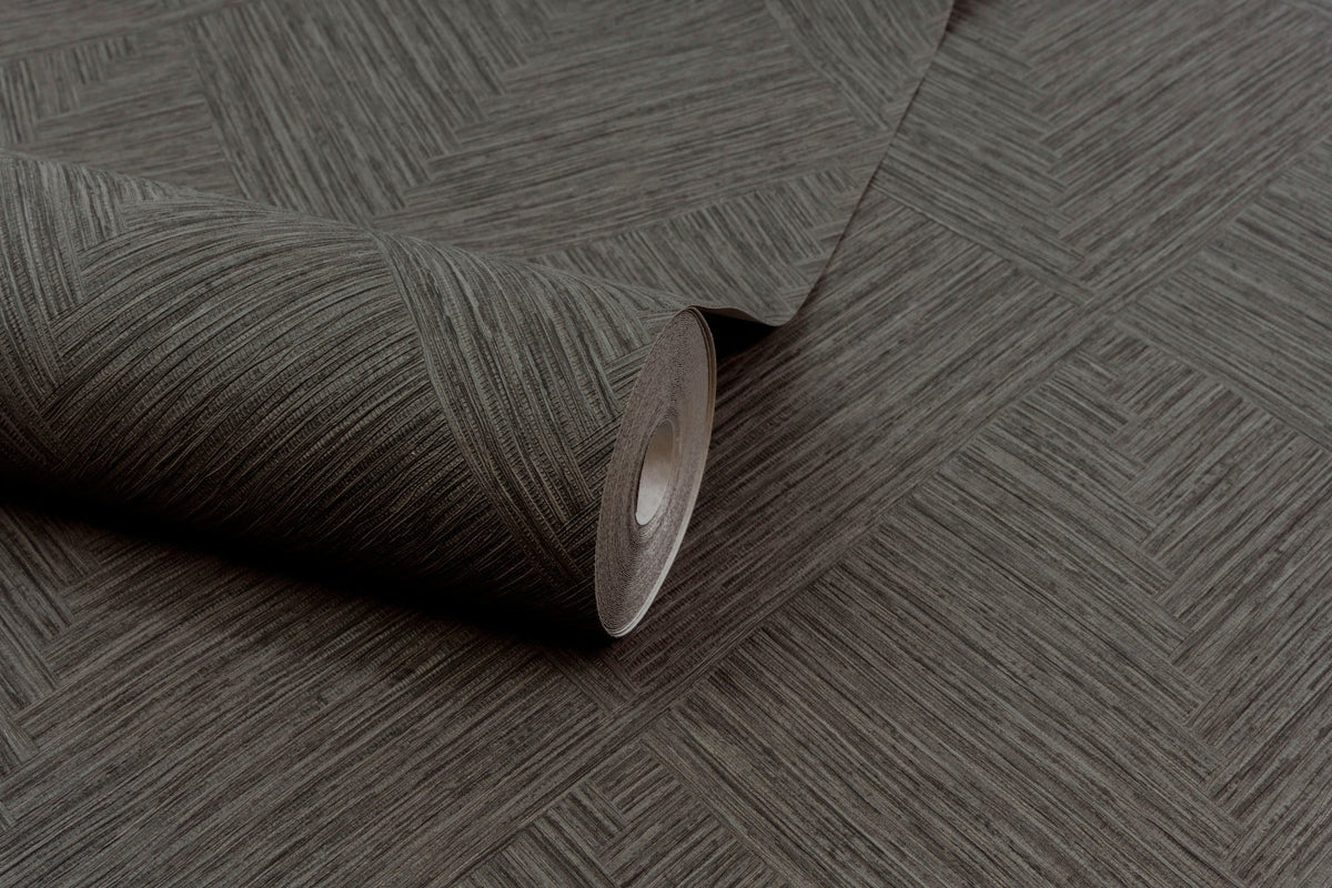 A partially unrolled roll of Chesapeake Hollis Textured Diamond Wallpaper by York Wallcoverings, featuring a subtle geometric diamond pattern in brown, is displayed on a matching surface.