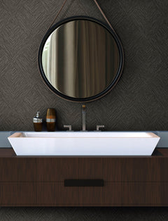 Modern bathroom with a round mirror, Chesapeake Hollis Textured Diamond Wallpaper by York Wallcoverings, rectangular white sink, and dark wood vanity. Soap dispensers are on the left side of the sink.