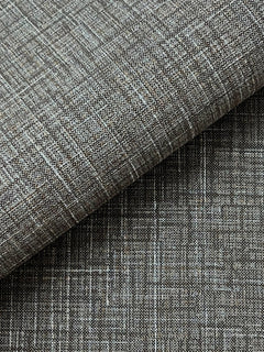 Close-up of Beau Faux Fabric Wallpaper by York Wallcoverings, showcasing a textured gray surface with a woven, crisscross pattern. One section is folded over, revealing a subtle variation in shading and texture.