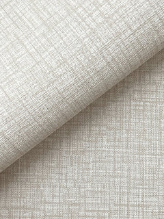 A close-up of York Wallcoverings’ Beau Faux Fabric Wallpaper, shown in beige with a subtle grid-like texture, partially folded over itself and casting a soft shadow across the lower half of the image.