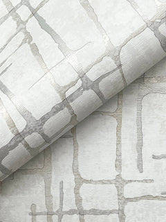 Introducing the Rian Linear Abstract Wallpaper by York Wallcoverings, featuring a rolled wallpaper design with a metallic silver and beige geometric pattern of intersecting lines on a subtly textured light background for a modern, abstract look.