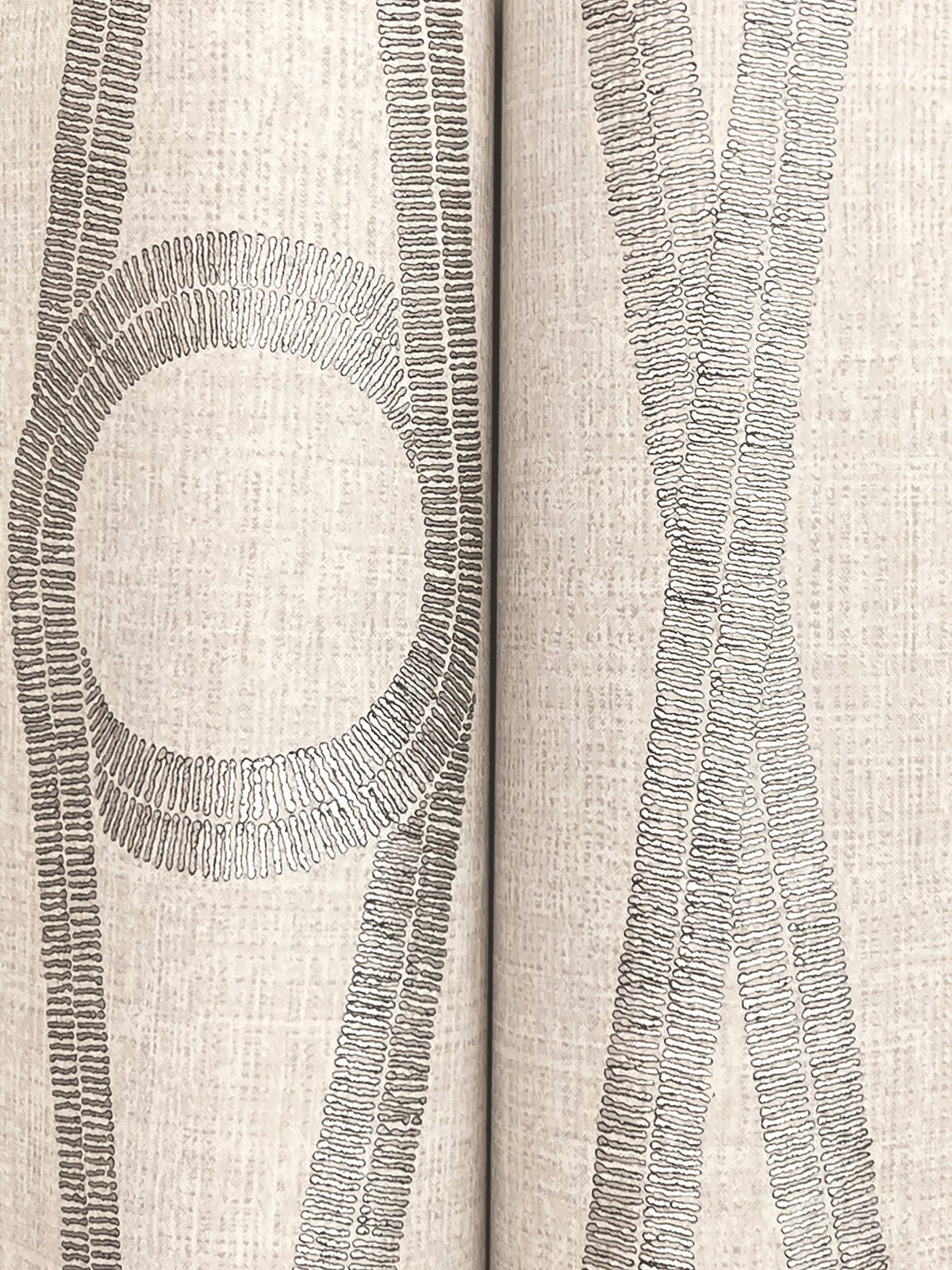 The Henlein Wallpaper by York Wallcoverings features a beige textured surface adorned with gray embroidered lines that create abstract shapes, including a circle on the left and intersecting lines on the right, with a vertical seam running down the center.