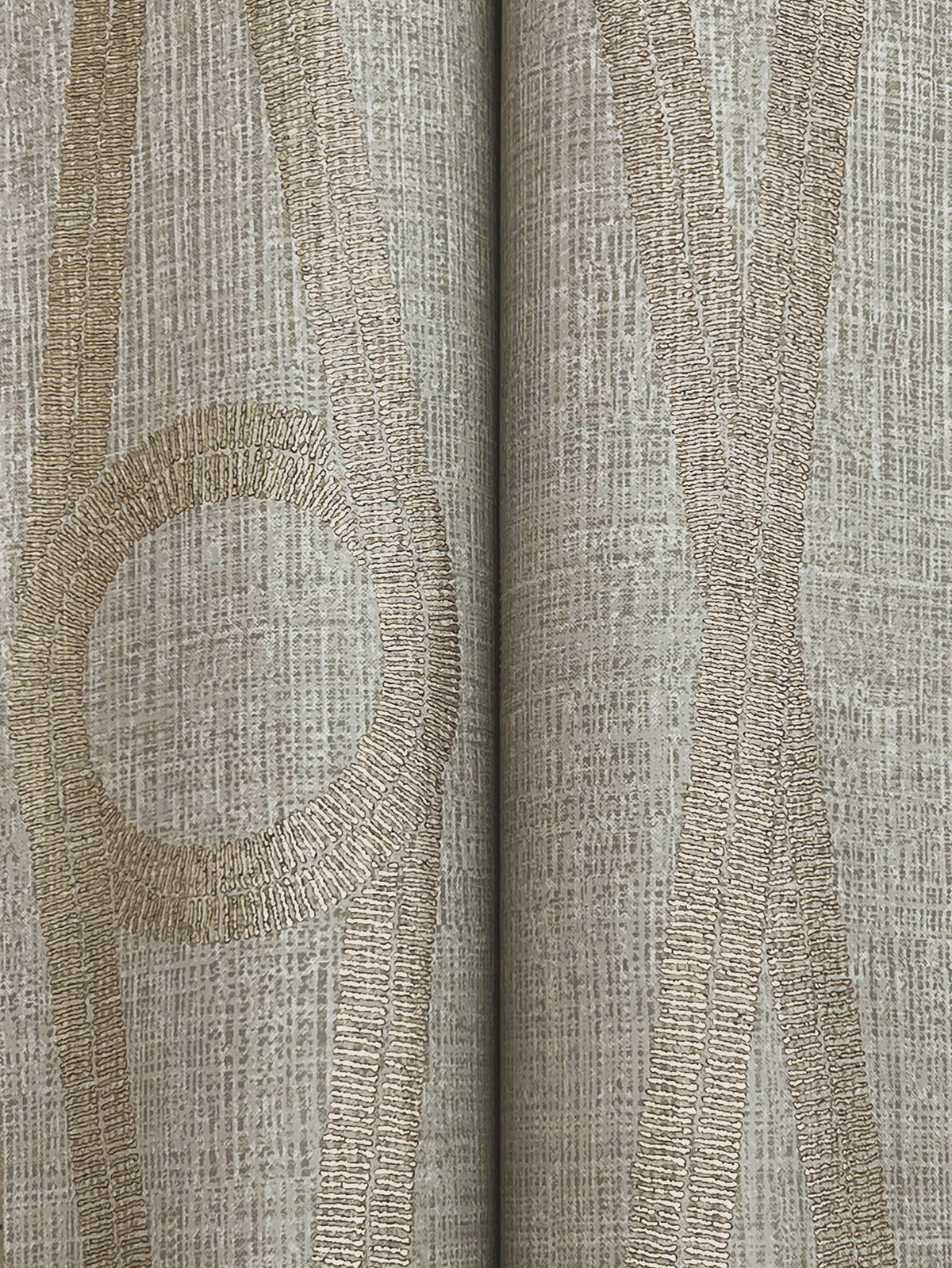 Close-up of the Henlein Wallpaper by York Wallcoverings, featuring beige and gold abstract lines and a large circle divided vertically down the center, set against a grid-like textured background.