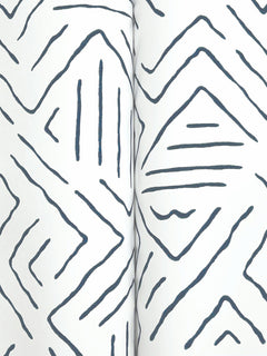 Close-up of Sirih Wallpaper by York Wallcoverings, featuring a white surface with abstract, hand-drawn dark blue zigzags and diamond shapes. Two vertical edges converge at the center, creating a subtle crease.