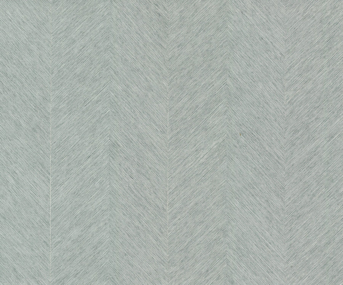 York Wallcoverings’ Chevron Wallpaper features a light gray textured surface adorned with a subtle herringbone pattern, created by fine, closely spaced diagonal lines that form repeating chevrons. This design imparts a gentle, woven sense of movement to any space.