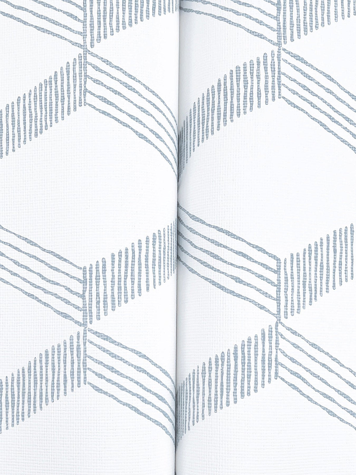 The Palisades Paperweave Wallpaper by York Wallcoverings features a white background adorned with a repeating pattern of blue zigzag diagonal lines and a vertical seam running down the center.