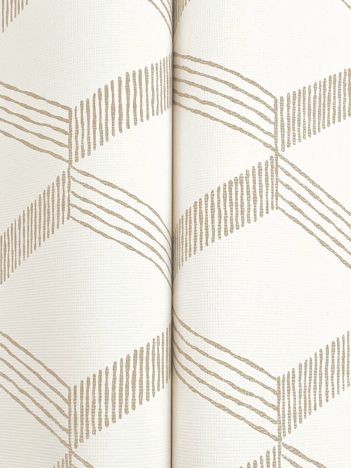 A close-up of the Palisades Paperweave Wallpaper by York Wallcoverings, featuring beige zigzag lines forming a geometric pattern on a white textured surface, with a vertical seam running down the center.