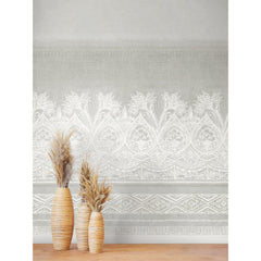 Three tall vases with dried grasses stand on a wooden floor in front of a light gray wall adorned with the Henna Wall Mural by York Wallcoverings, featuring an intricate white floral and geometric pattern.