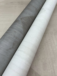 Two rolls of In Clay Wallpaper featuring a subtle geometric pattern in shades of gray and white.