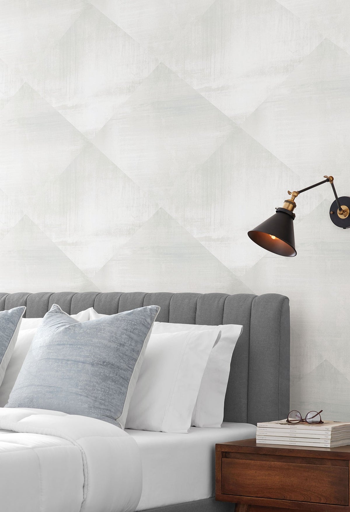 In Clay Wallpaper featuring a light gray and white geometric diamond pattern with a subtle textured finish behind a bed with a dark gray headboard.