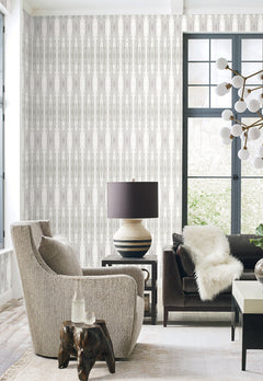 Escalante Wallpaper by York Wallcoverings featuring a vertical, abstract striped pattern in shades of gray and white on a living room wall.