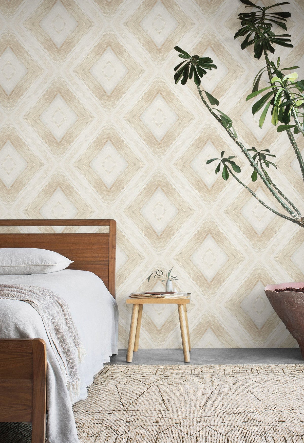 Ballad Wallpaper featuring a large-scale, beige and white diamond pattern with a soft, painted texture behind a bedroom setting.