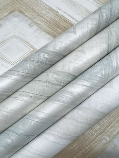 Four rolls of Ballad Wallpaper by York Wallcoverings, featuring a neutral, marbled pattern with subtle diagonal geometric lines.