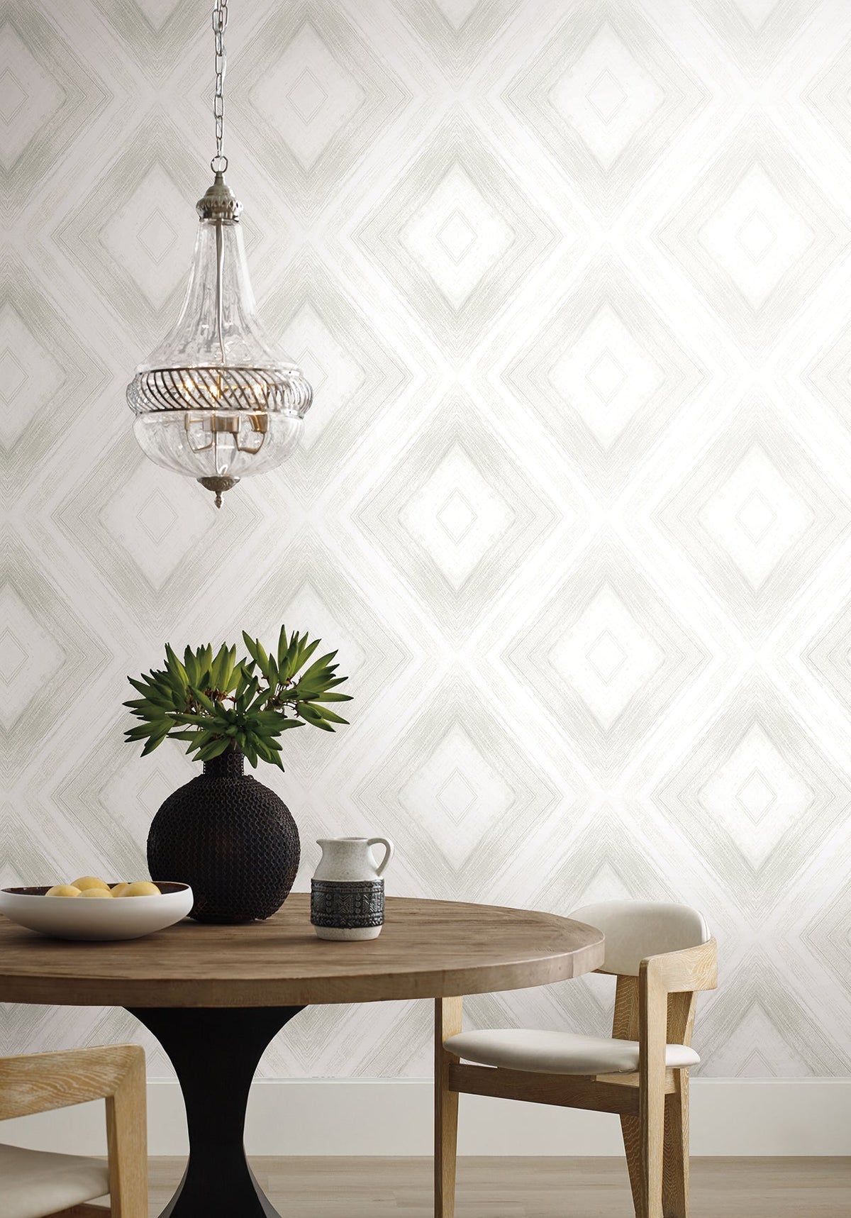 Ballad Wallpaper featuring a repeating diamond pattern in soft gray lines on a white background, displayed behind a dining table with a decorative vase and a pendant light.