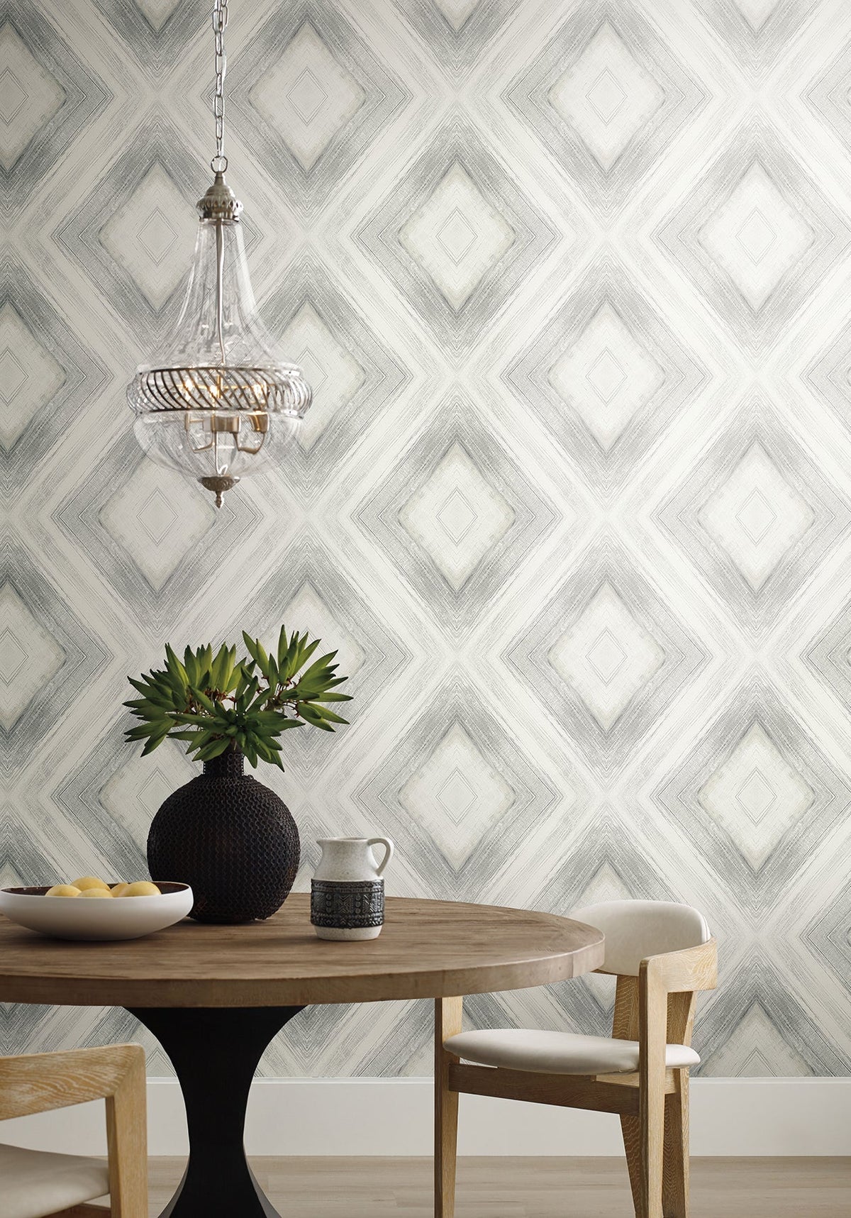 Ballad black wallpaper in a dining room with a round wooden table, white chairs, and a glass pendant lamp.
