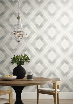 Ballad black wallpaper in a dining room with a round wooden table, white chairs, and a glass pendant lamp.