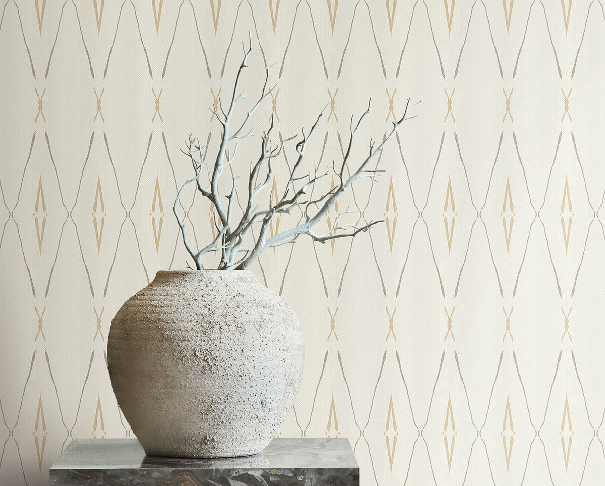 A textured stone vase holding bare branches sits in front of Artifact Silhouettes Wallpaper featuring a repeating geometric diamond pattern.