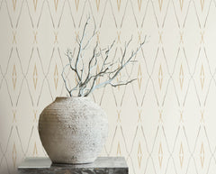 A textured stone vase holding bare branches sits in front of Artifact Silhouettes Wallpaper featuring a repeating geometric diamond pattern.