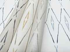 Three rolls and one flat sheet of York Wallcoverings Artifact Silhouettes wallpaper, featuring a repeating diamond and cross pattern in gray, tan, and blue.