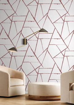 Intersect Wallpaper featuring a pattern of intersecting dark pink lines on a white background, with a two-armed wall lamp mounted above two cream-colored chairs and a matching ottoman.