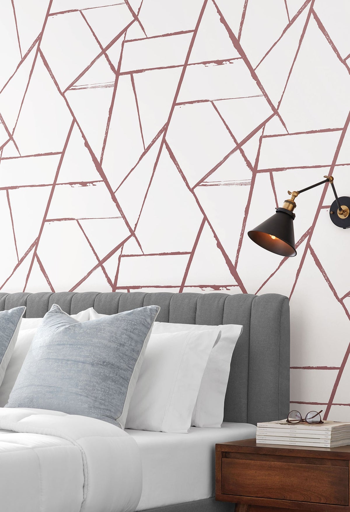 Intersect Wallpaper featuring a geometric pattern of intersecting, distressed mauve lines on a white background, installed behind a gray tufted headboard.
