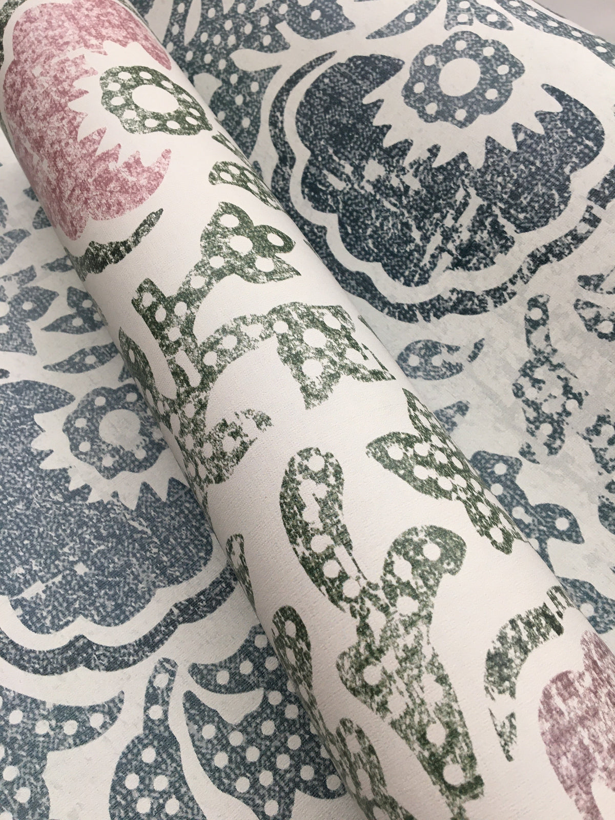 Blaise Wallpaper roll featuring a distressed floral and paisley pattern in shades of pink, green, and blue on a white background.