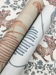 Two rolls of Blaise Wallpaper featuring illustrations of tigers among leaves and botanical patterns.
