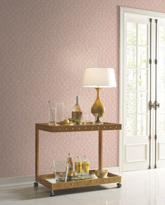 Candice Olson Luminous Gingko Wallpaper in pink with a repeating white gingko leaf pattern on a wall behind a two-tiered gold bar cart.