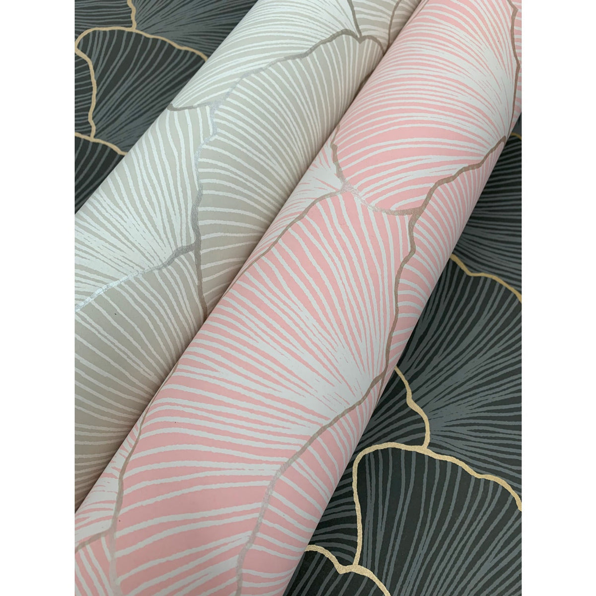 Three rolls of Candice Olson Luminous Gingko Wallpaper in pink, light grey, and charcoal grey, each featuring a gingko leaf pattern with metallic-toned outlines.