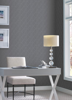 A white desk and chair set against a dark gray Candice Olson Opposites Attract Wallpaper by York Wallcoverings, featuring a repeating geometric leaf pattern.